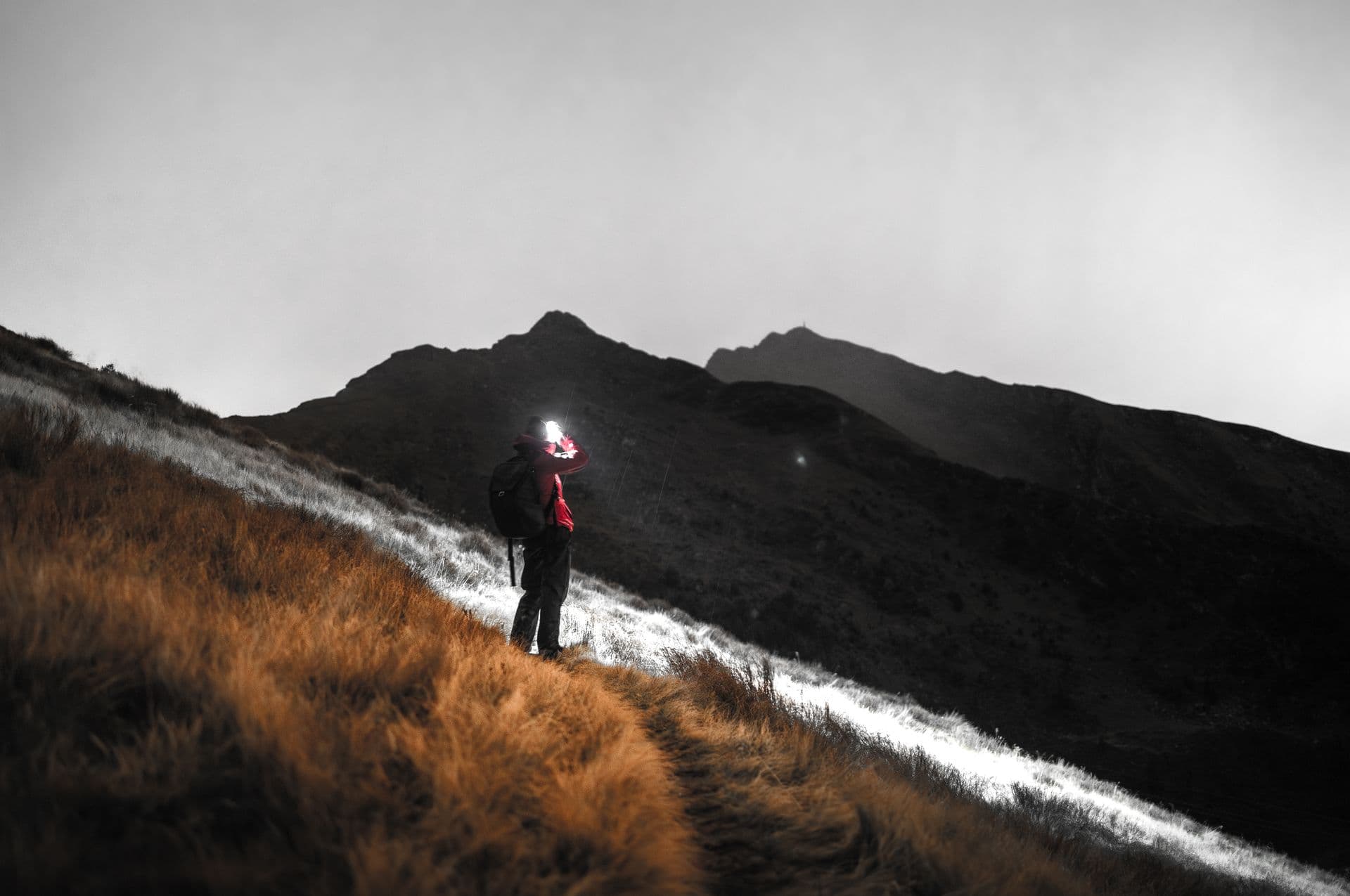 A figure crossing a dark mountainside at dusk